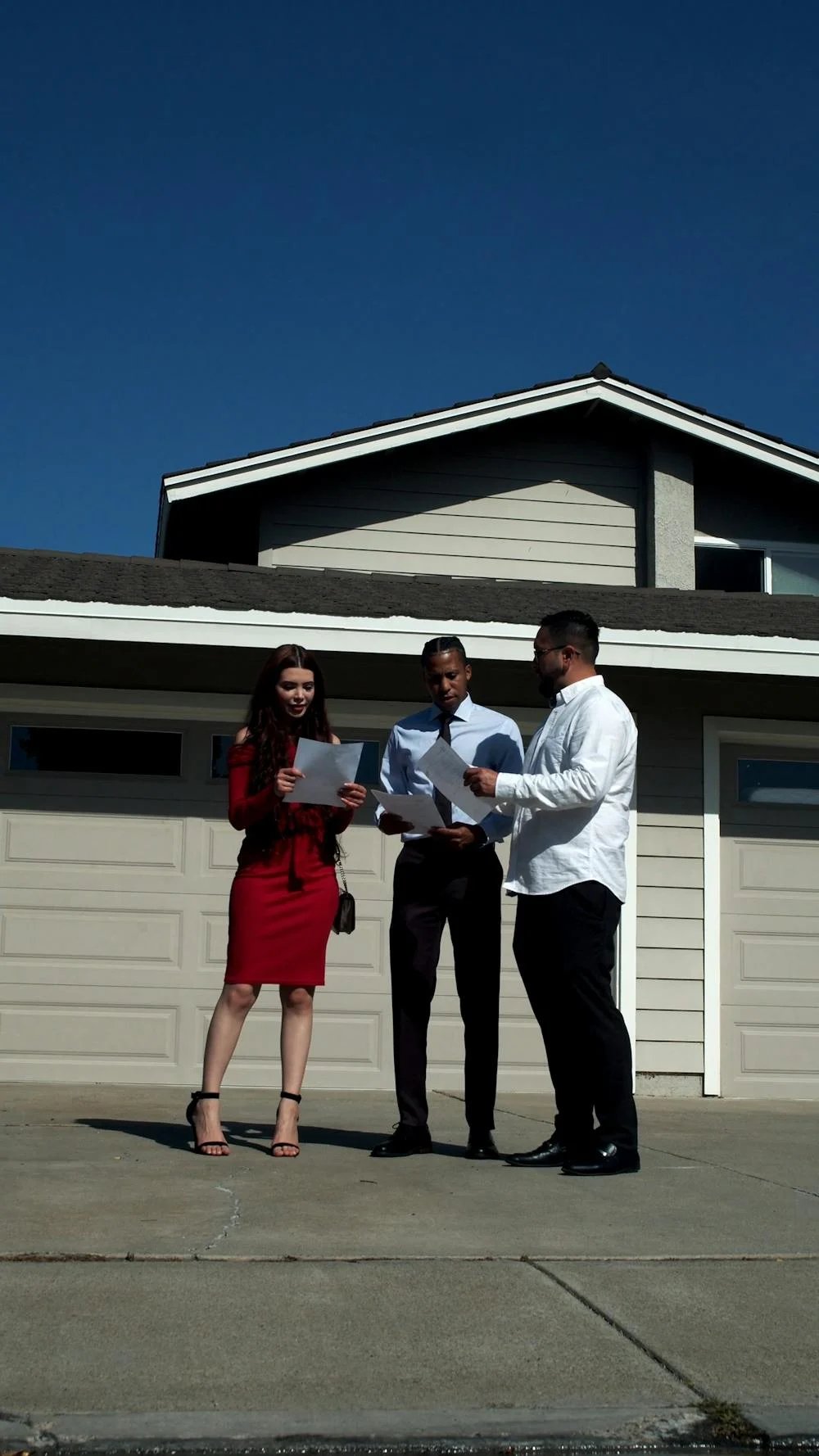 Real estate professional reviewing property documents with buyers outside a home