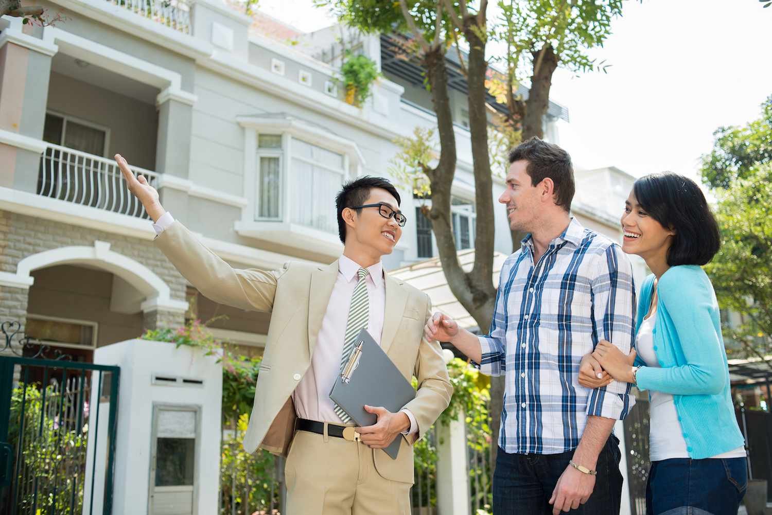 Real estate agent showing a property to prospective homebuyers outside a home